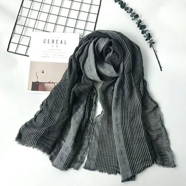 Solid long scarf draped over women's shoulders outdoors