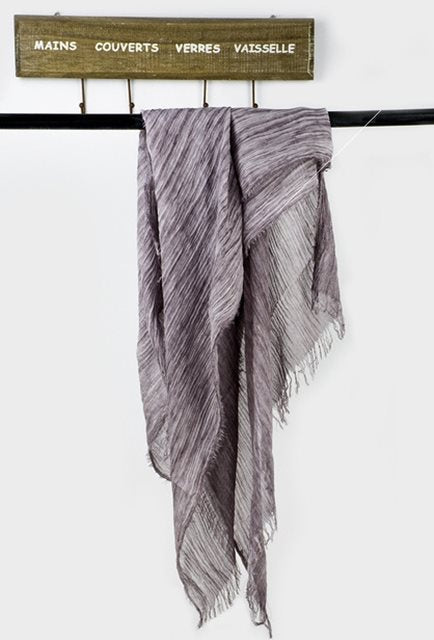 Solid long scarf draped over women's shoulders outdoors