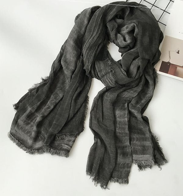 Solid long scarf draped over women's shoulders outdoors