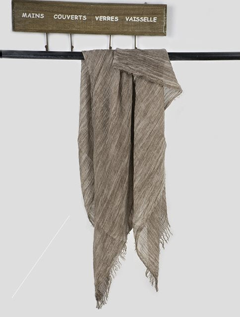 Solid long scarf draped over women's shoulders outdoors