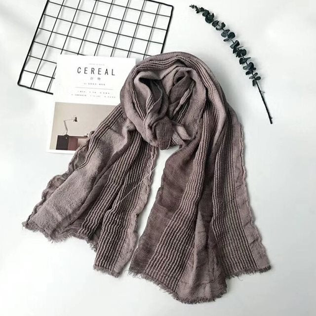 Solid long scarf draped over women's shoulders outdoors