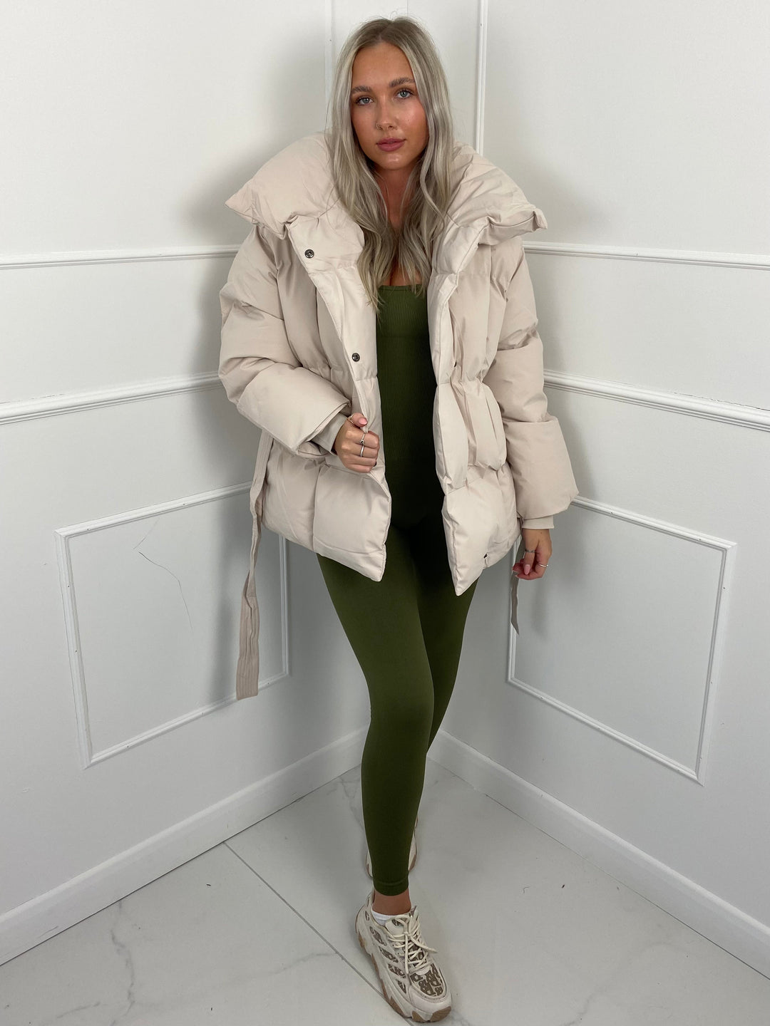Woman wearing quilted puffer jacket with matching belt outdoors