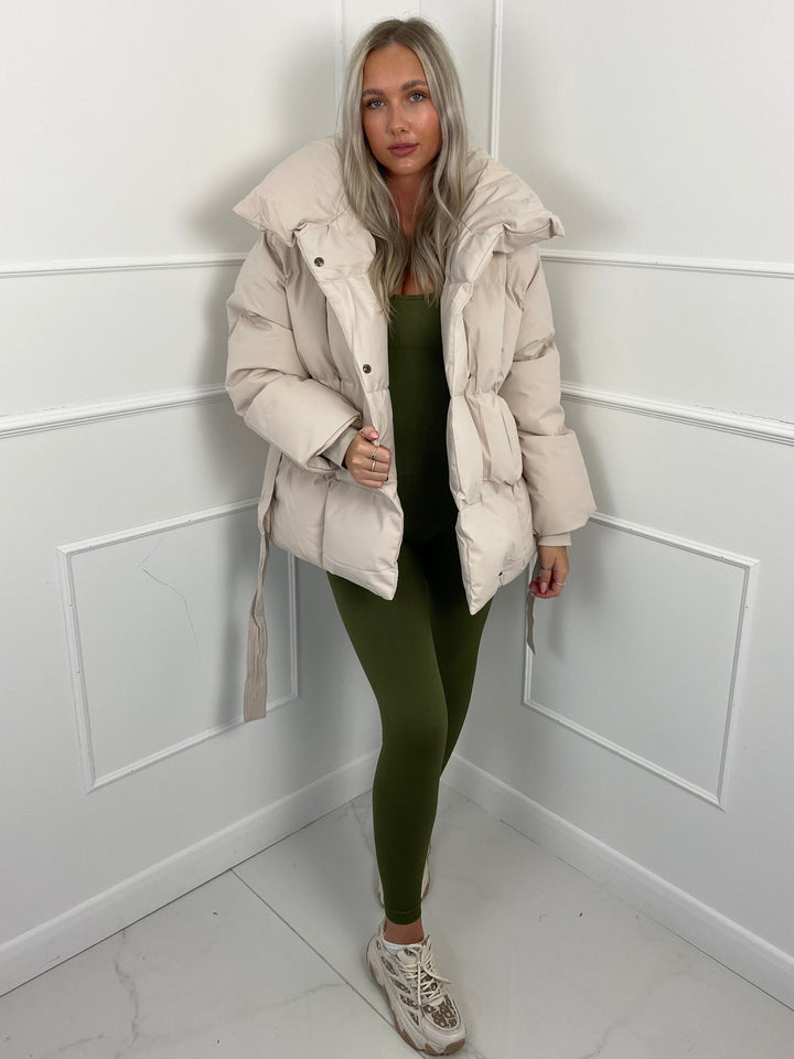 Woman wearing quilted puffer jacket with matching belt outdoors