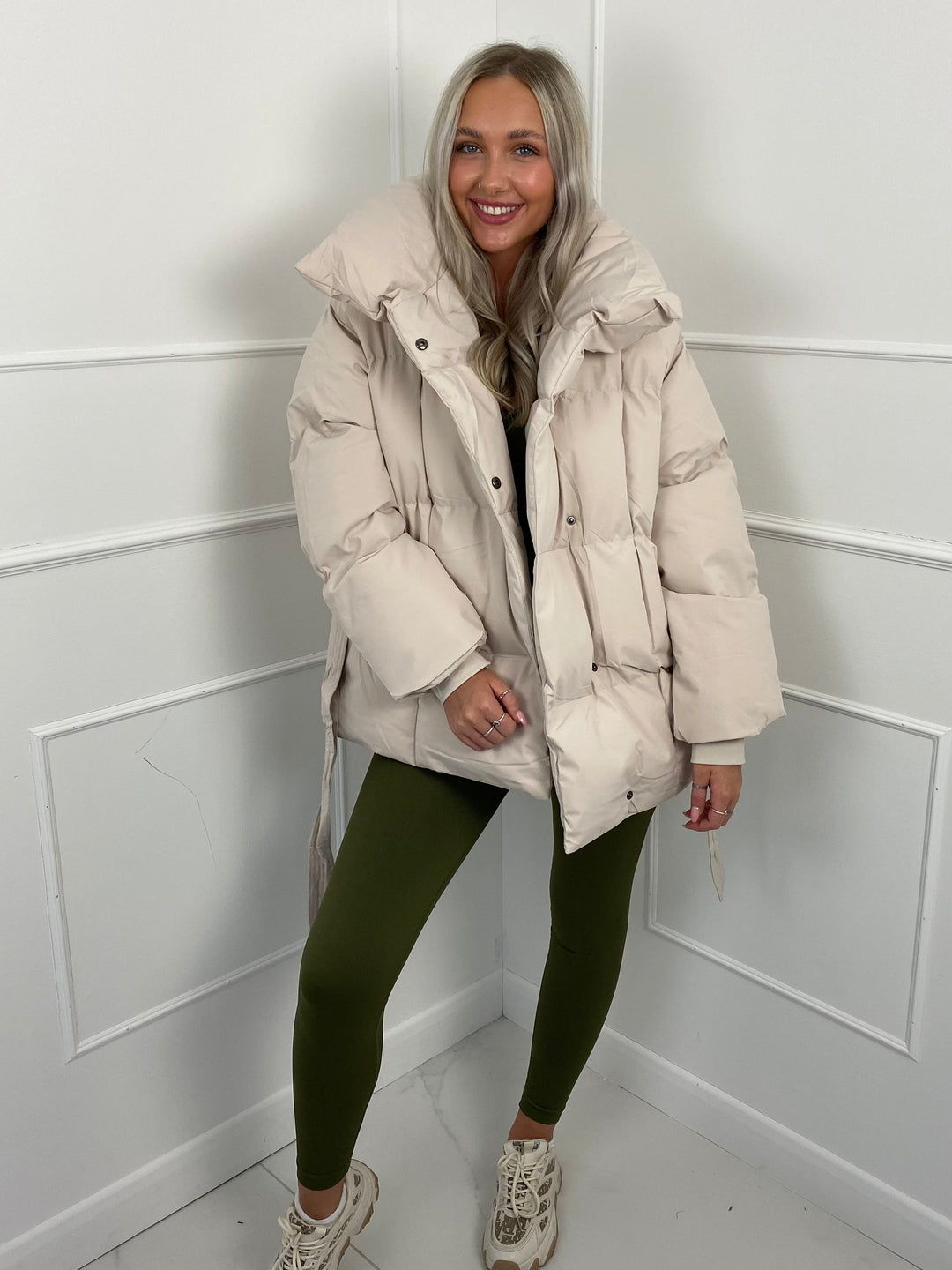 Woman wearing quilted puffer jacket with matching belt outdoors