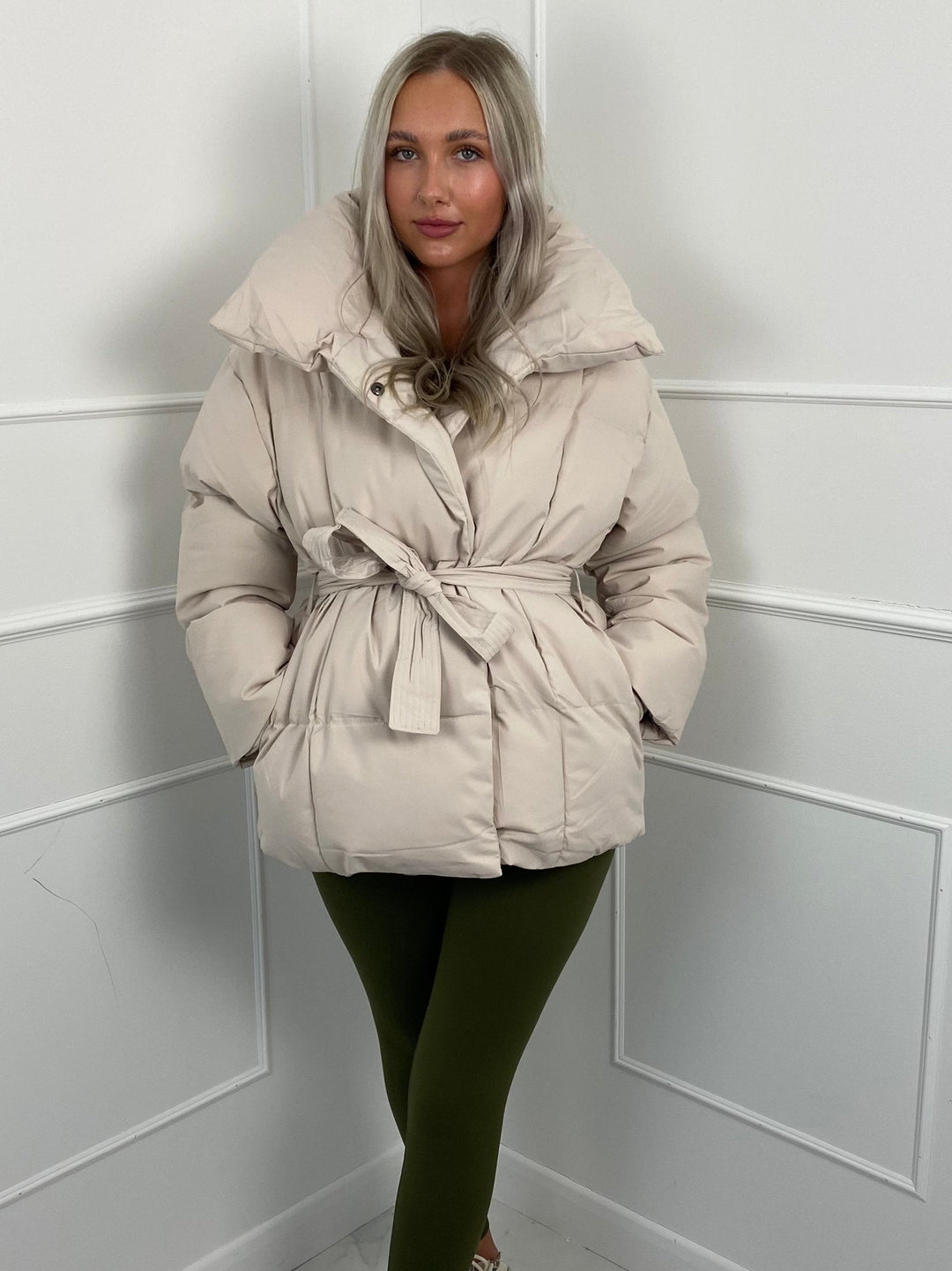 Woman wearing quilted puffer jacket with matching belt outdoors
