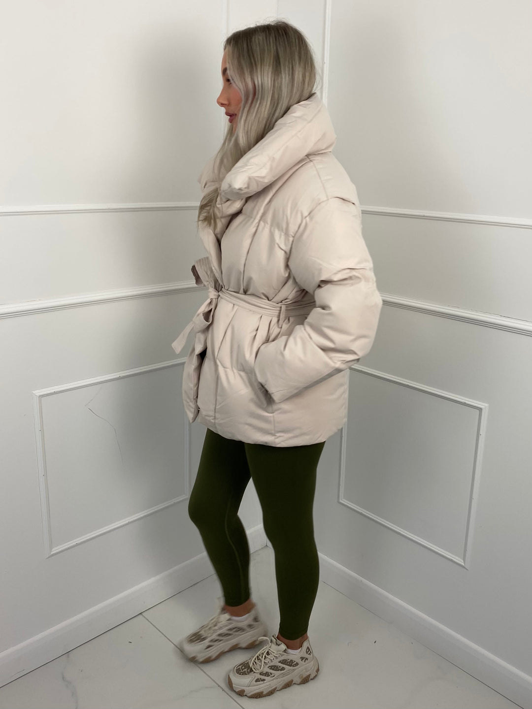 Woman wearing quilted puffer jacket with matching belt outdoors