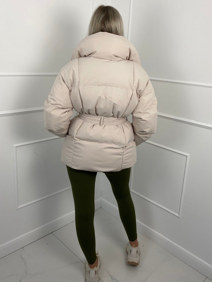 Woman wearing quilted puffer jacket with matching belt outdoors