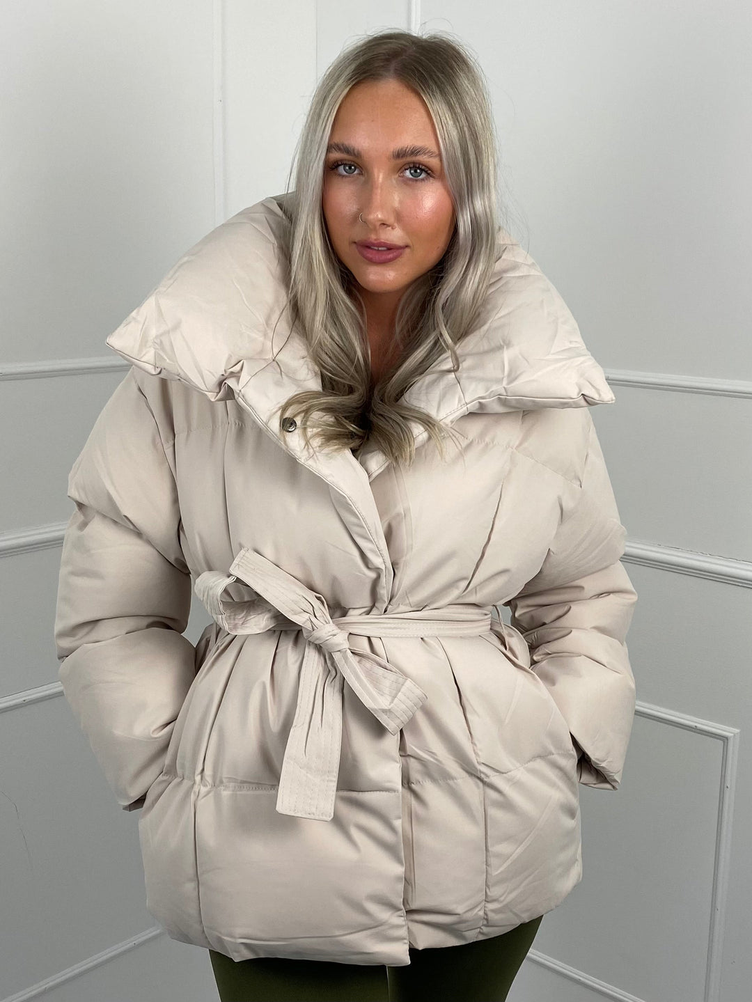 Woman wearing quilted puffer jacket with matching belt outdoors