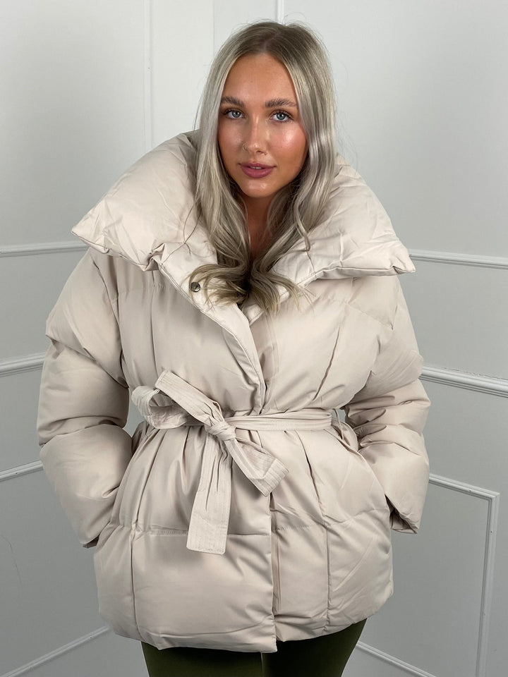 Woman wearing quilted puffer jacket with matching belt outdoors