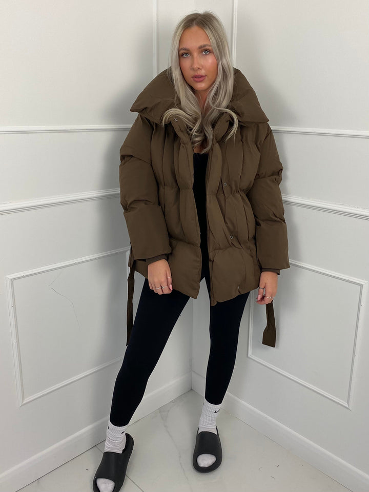Woman wearing quilted puffer jacket with matching belt outdoors