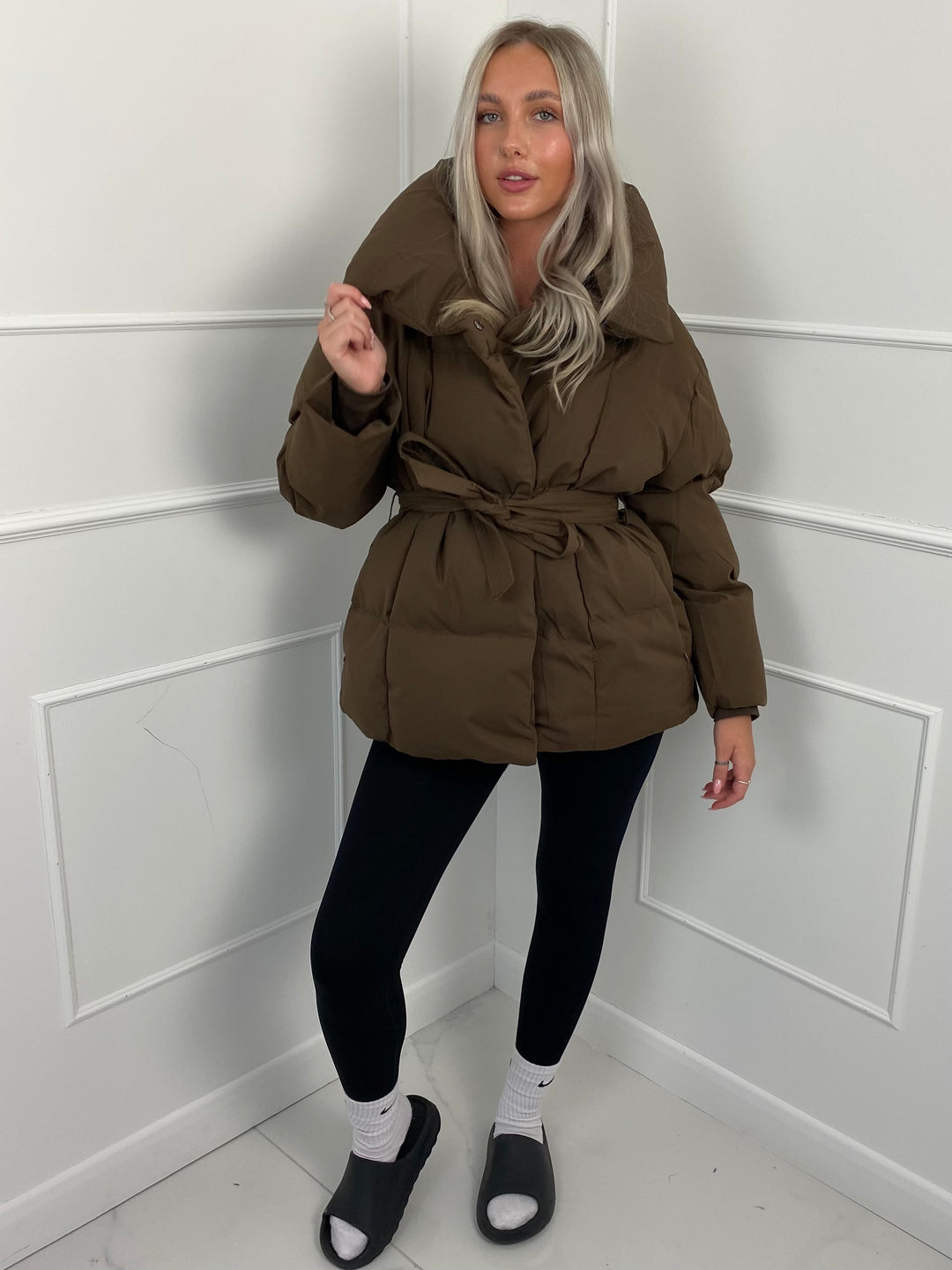 Woman wearing quilted puffer jacket with matching belt outdoors