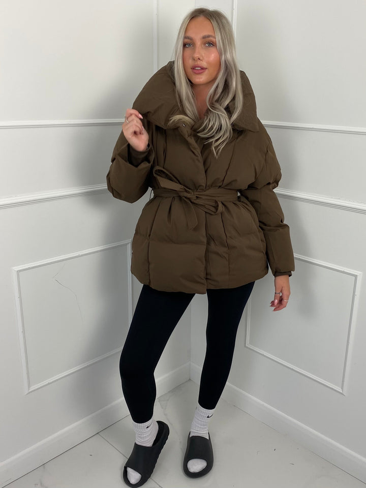 Woman wearing quilted puffer jacket with matching belt outdoors