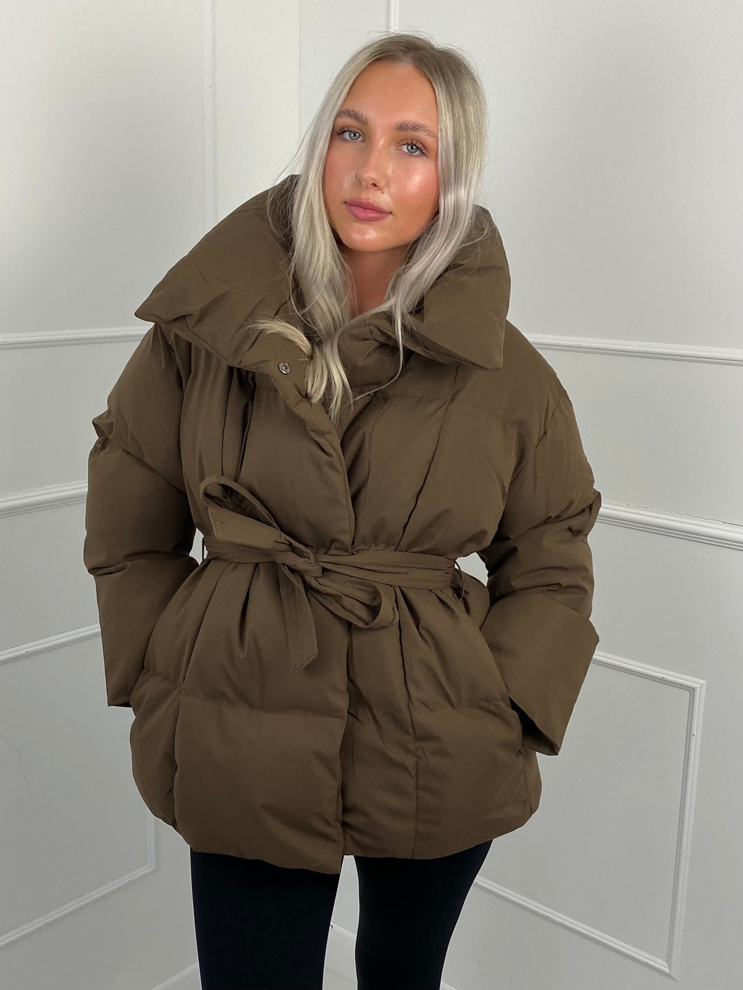 Woman wearing quilted puffer jacket with matching belt outdoors