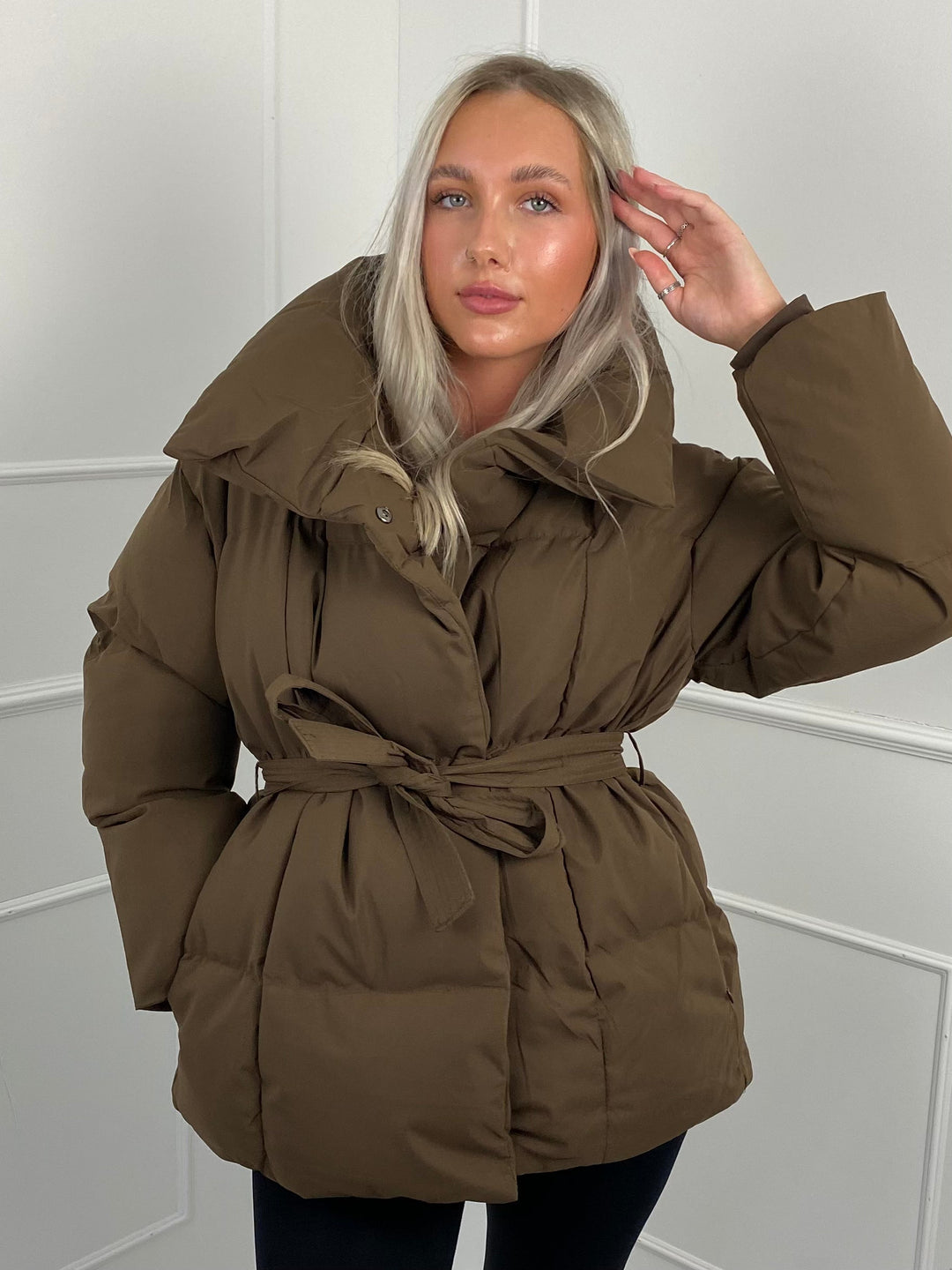 Woman wearing quilted puffer jacket with matching belt outdoors