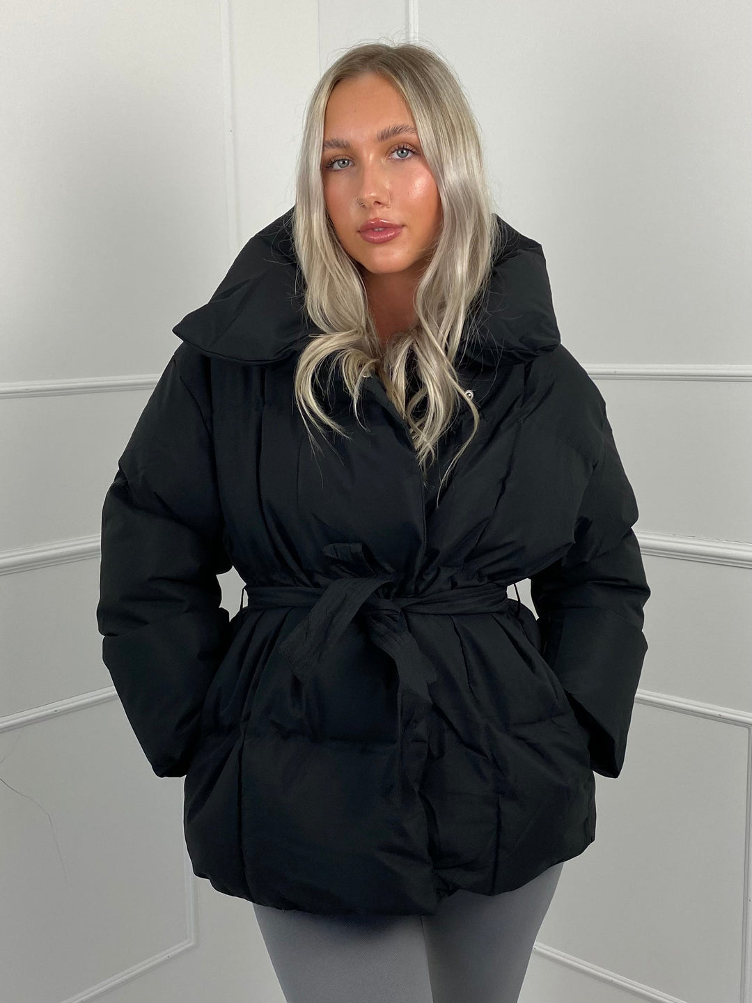 Woman wearing quilted puffer jacket with matching belt outdoors