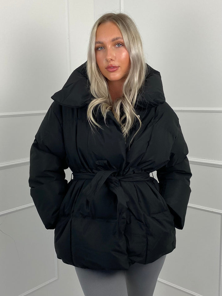 Woman wearing quilted puffer jacket with matching belt outdoors